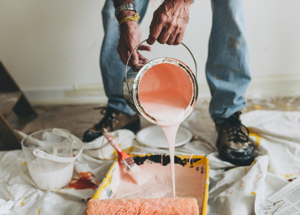 a person pouring pink paint into a container