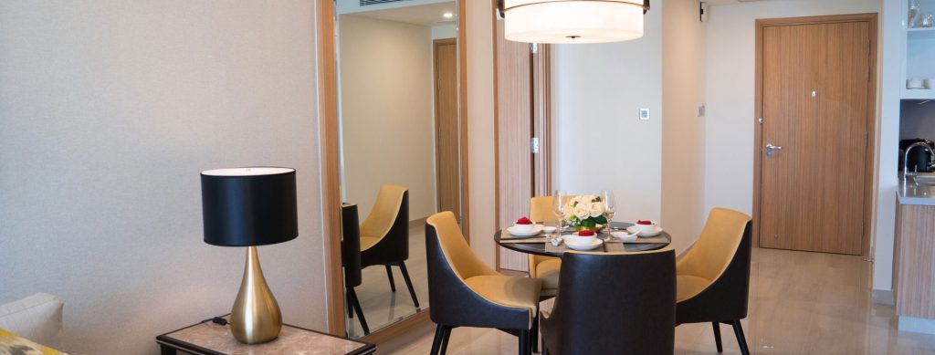 Interior shot of a modern dining room with a round table set for four, chairs, a lamp, & a mirror.